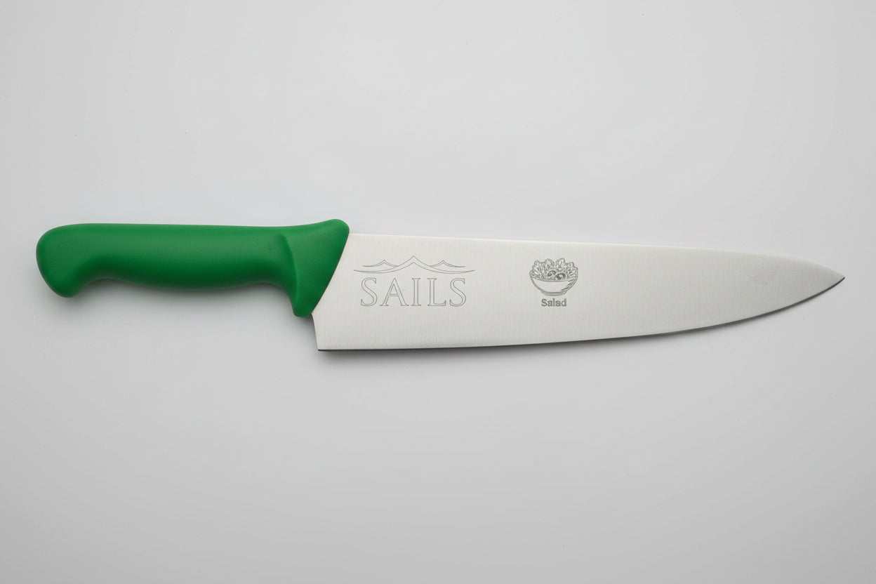 Knife with a green handle held by a hand on a rocky surface