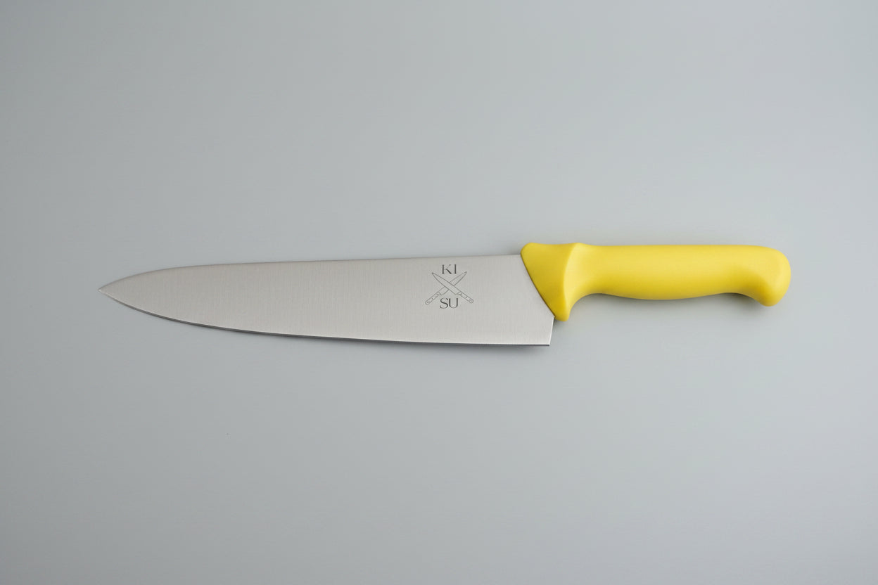 Knife with yellow handle and metal blade on a wooden surface, next to a ruler for scale.