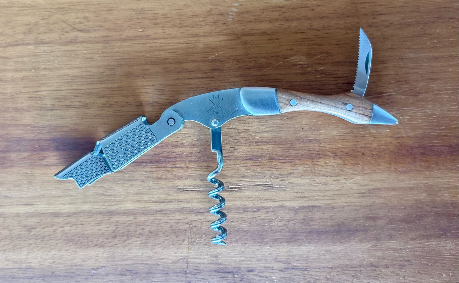 Rosewood wine corkscrew with stainless steel tip and double hinged design on wooden surface.